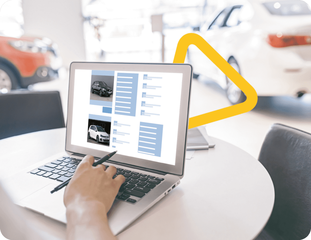 Laptop mit Fahrzeugen und Fahrzeugdaten, mit einem Autohaus im Hintergrund